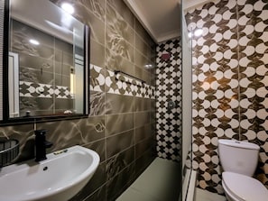 Een badkamer met een wit wastafelmeubel, een spiegel, een toilet en decoratieve tegels op de wanden.