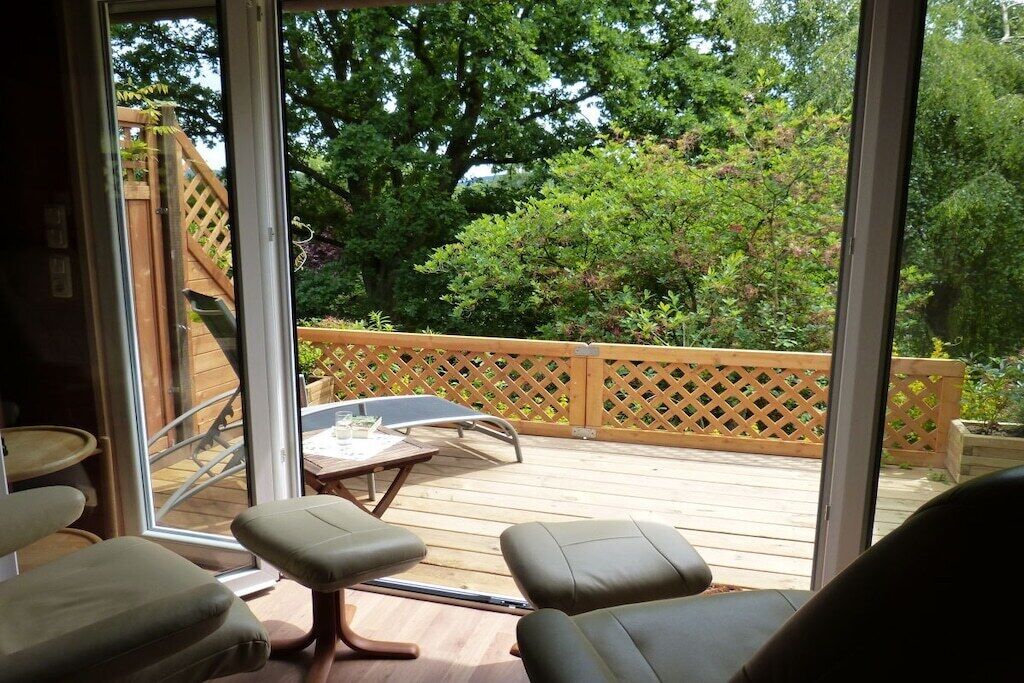 A deck with a wooden railing, a table, and two chairs.