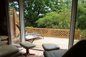 Een terras met houten balustrade, een tafel en twee stoelen.