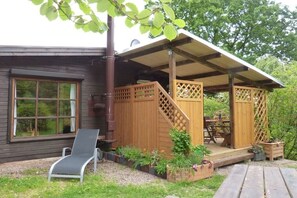 A wooden house with a covered porch, a window, and a chair. - Holiday home Berghaus (Reinhardshagen)