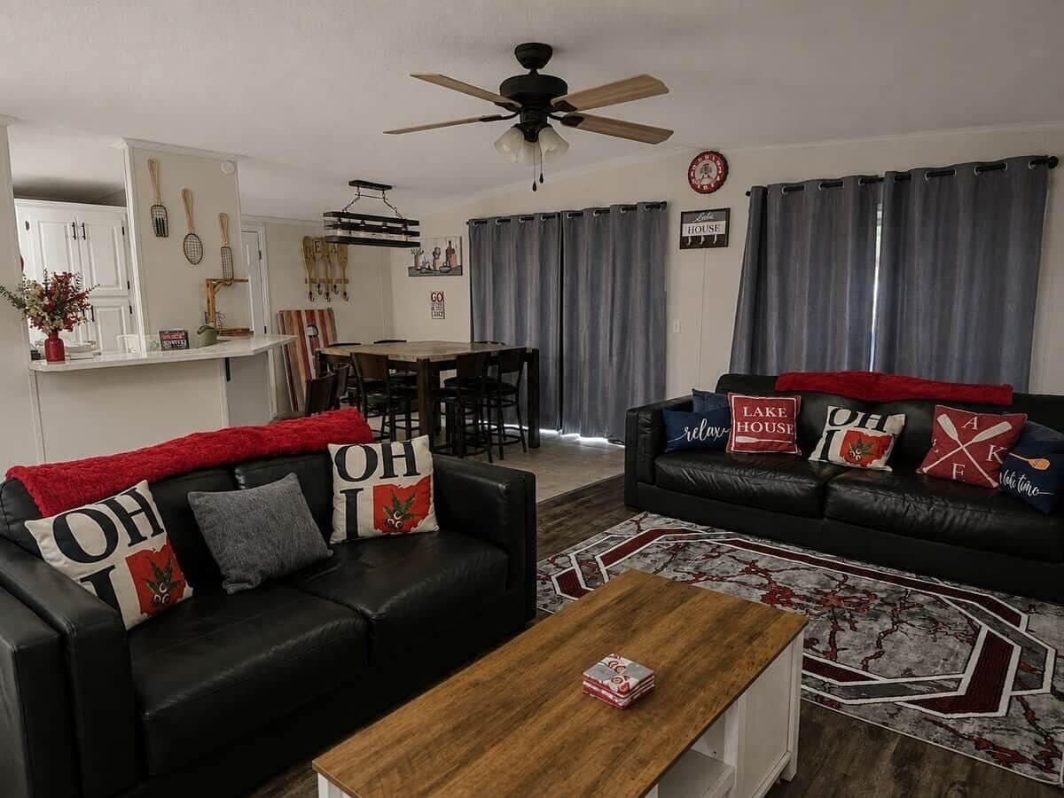 A living room with two black leather sofas, a wooden coffee table, and a ceiling fan.