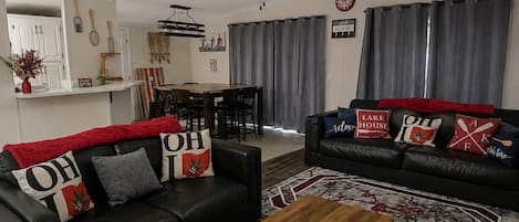A living room with two black leather sofas, a wooden coffee table, and a ceiling fan.