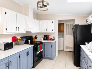 A kitchen with white cabinets, a black stove, and a black refrigerator. - Buckeye Island Paradise (Put-in-Bay Township)