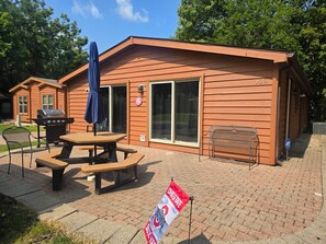 A wooden cabin with a patio area, a grill, and a flag indicating Ohio State University. - Buckeye Island Paradise (Put-in-Bay Township)