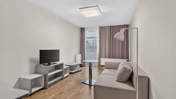 Una sala de estar moderna con un televisor de pantalla plana, un sofá gris, una mesita y una lámpara de pie.