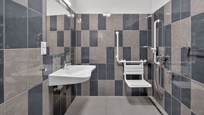 Un baño moderno con un lavabo blanco, una repisa de vidrio, un inodoro blanco y una zona de ducha.