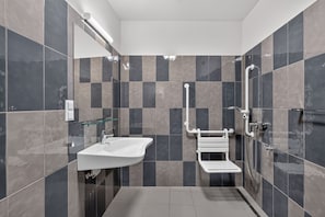 Ein modernes Badezimmer mit Waschbecken, Glasablage, Toilette und Duschbereich.