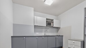 A modern kitchen with grey cabinets, a microwave, and a sink.