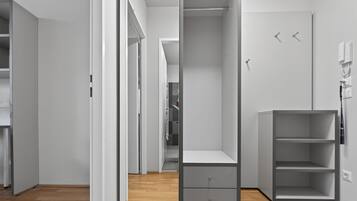 A modern, minimalist room with a built-in wardrobe, a small desk, and a shelving unit.