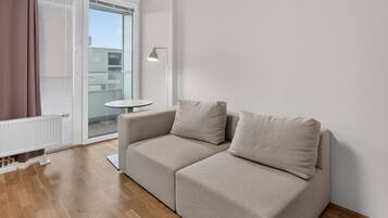 A modern living room with a beige sofa, a small round table, and a floor lamp.