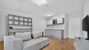 A modern living room with a grey sofa, a flat-screen TV, and a wooden floor.