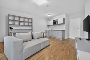 A modern living room with a grey sofa, a flat-screen TV, and a wooden floor.