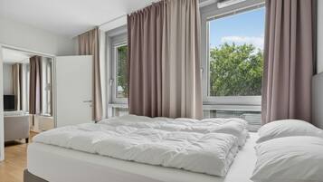 Une chambre à coucher avec un grand lit, un bureau et une fenêtre avec des rideaux.