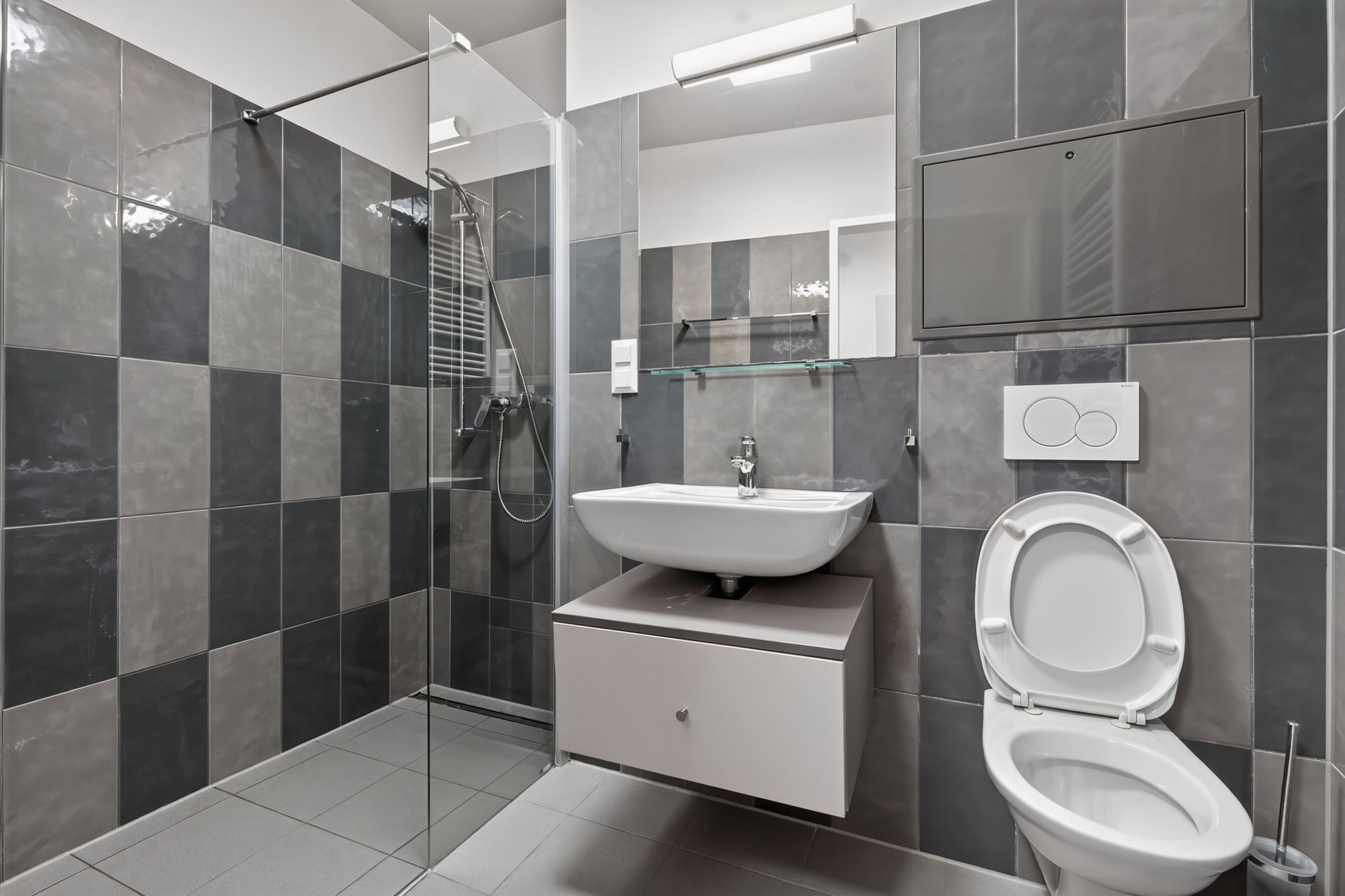 Un baño moderno con cabina de ducha de vidrio, un lavabo blanco y un inodoro.