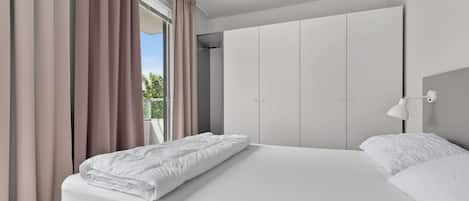 Un dormitorio moderno con una cama grande, un armario y una ventana con cortinas.