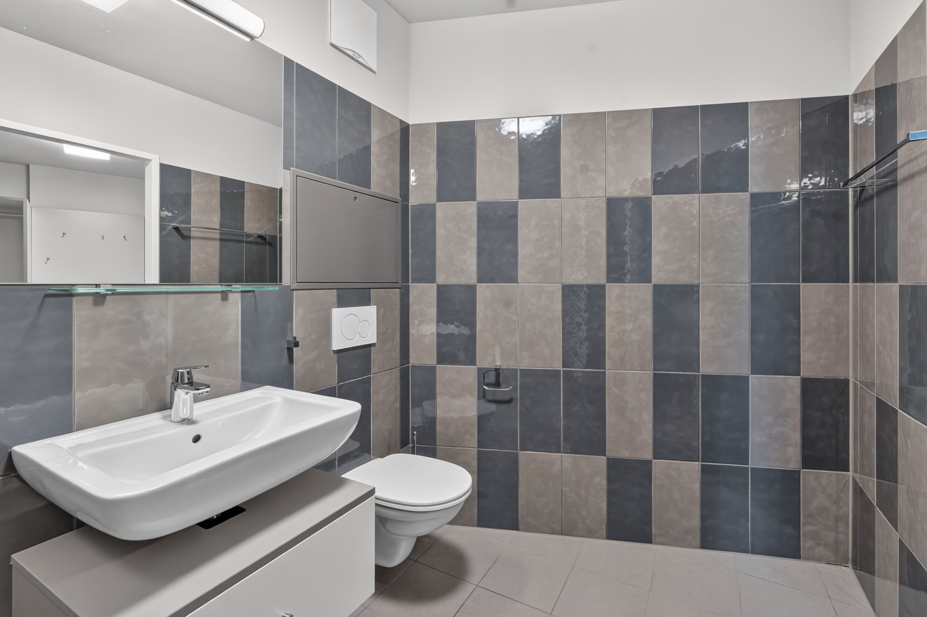 A modern bathroom with a white sink, a toilet, and a shower area.