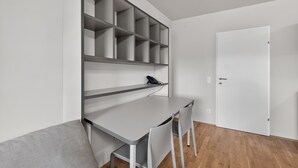 A modern room with a desk, chairs, and a white door.