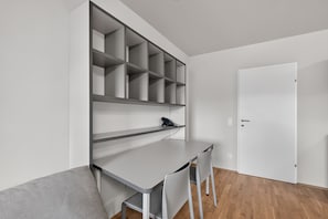 A modern room with a desk, chairs, and a white door.
