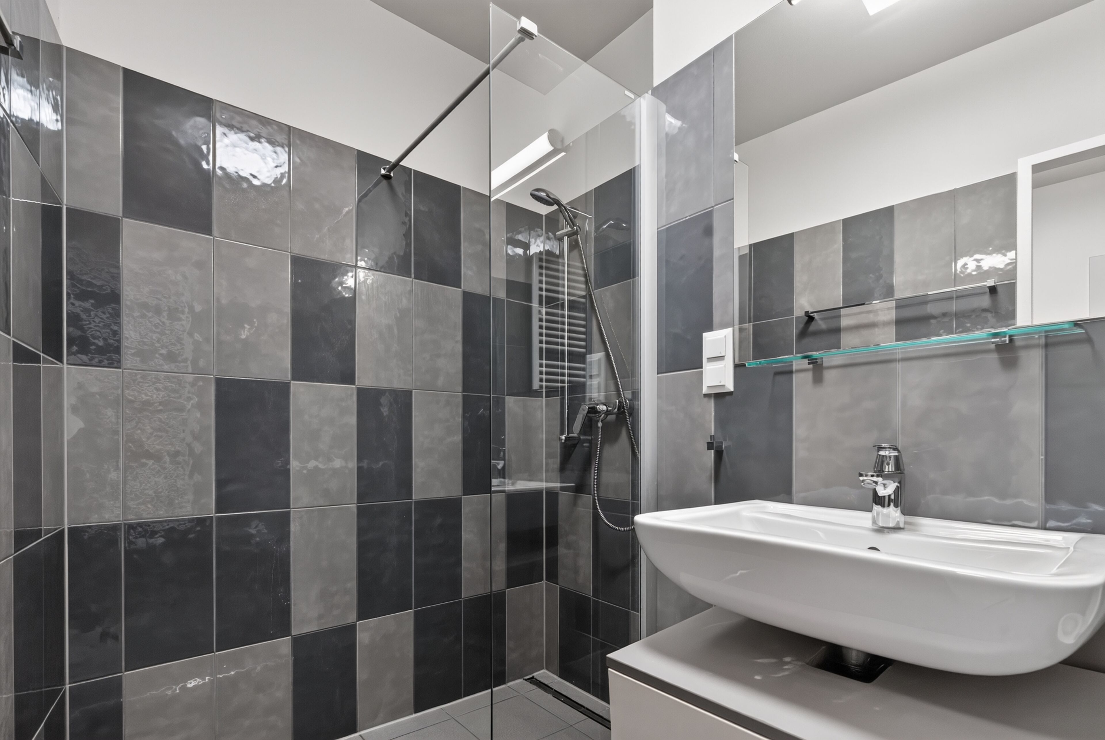 A modern bathroom with a shower, a sink, and a glass shelf.