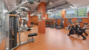 Un gimnasio con diverso equipo de ejercicio, incluyendo cintas de correr, bicicletas estáticas y máquinas de pesas.