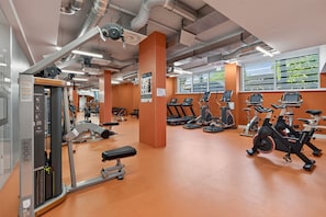 Ein Fitnessstudio mit verschiedenen Trainingsgeräten, darunter Laufbänder, Ergometer und Kraftgeräte.