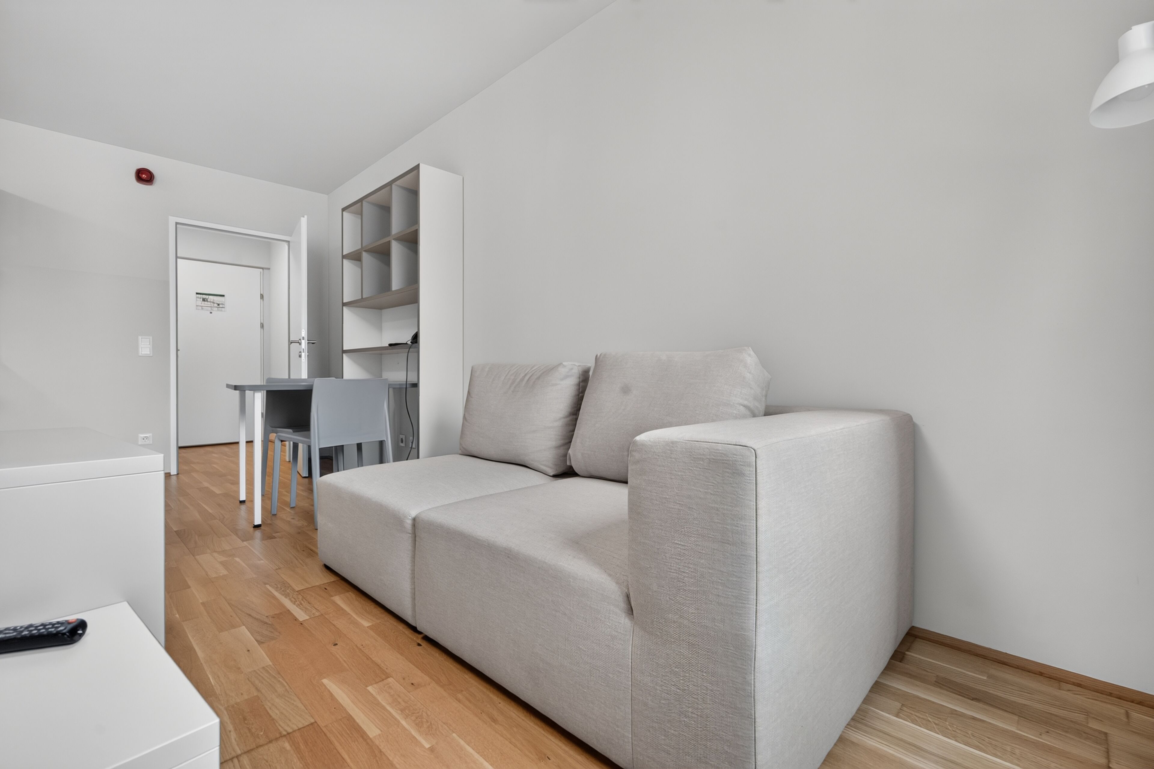 A modern living room with a grey sofa, a small table, and a white cabinet.