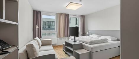 Habitación de hotel moderna con cama, escritorio, silla y ventana con cortinas.