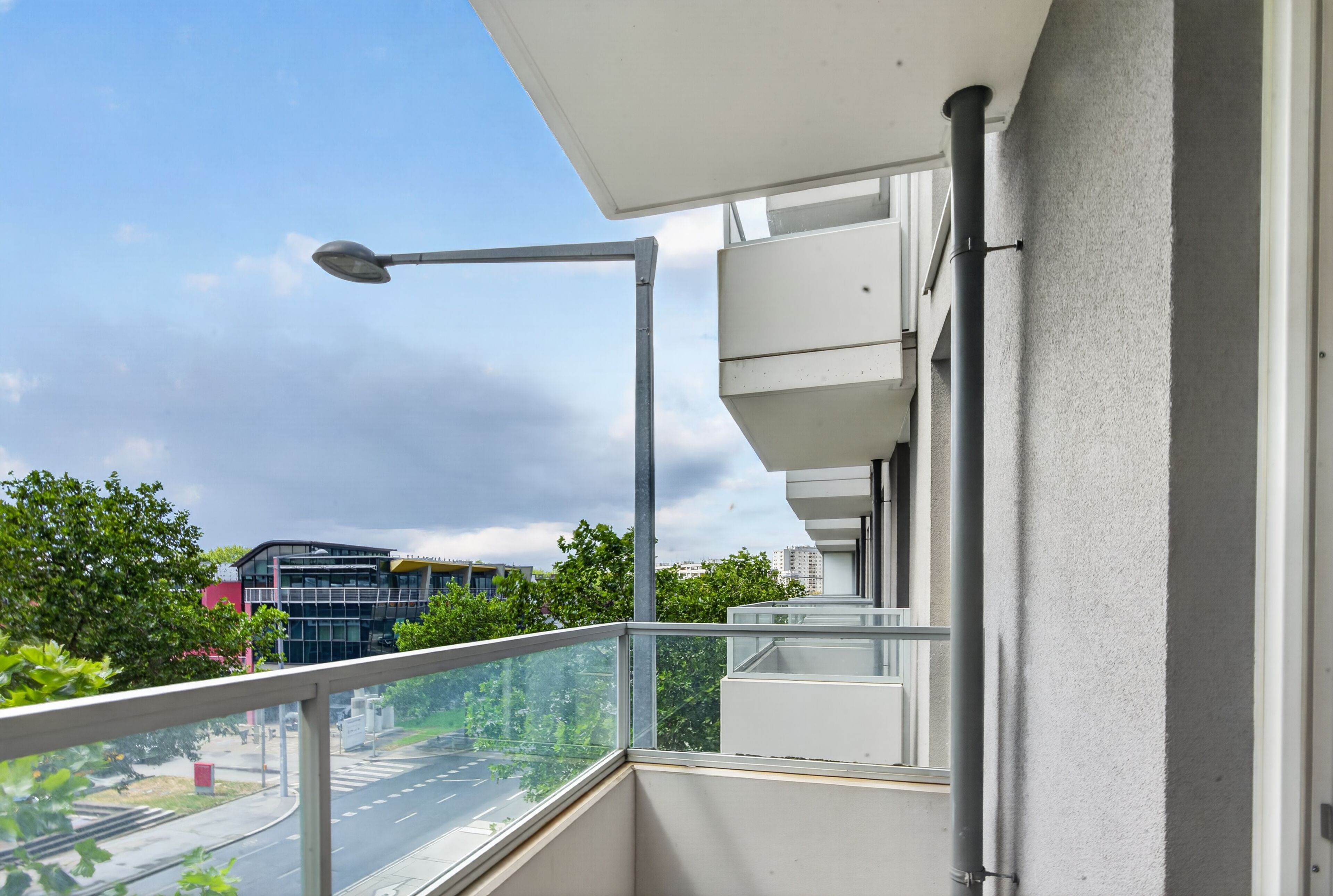 Ein Balkon mit freiem Blick auf die Straße und die umliegenden Gebäude.