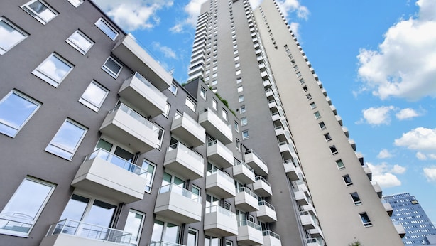 Un edificio residencial alto con varios balcones y un cielo despejado.
