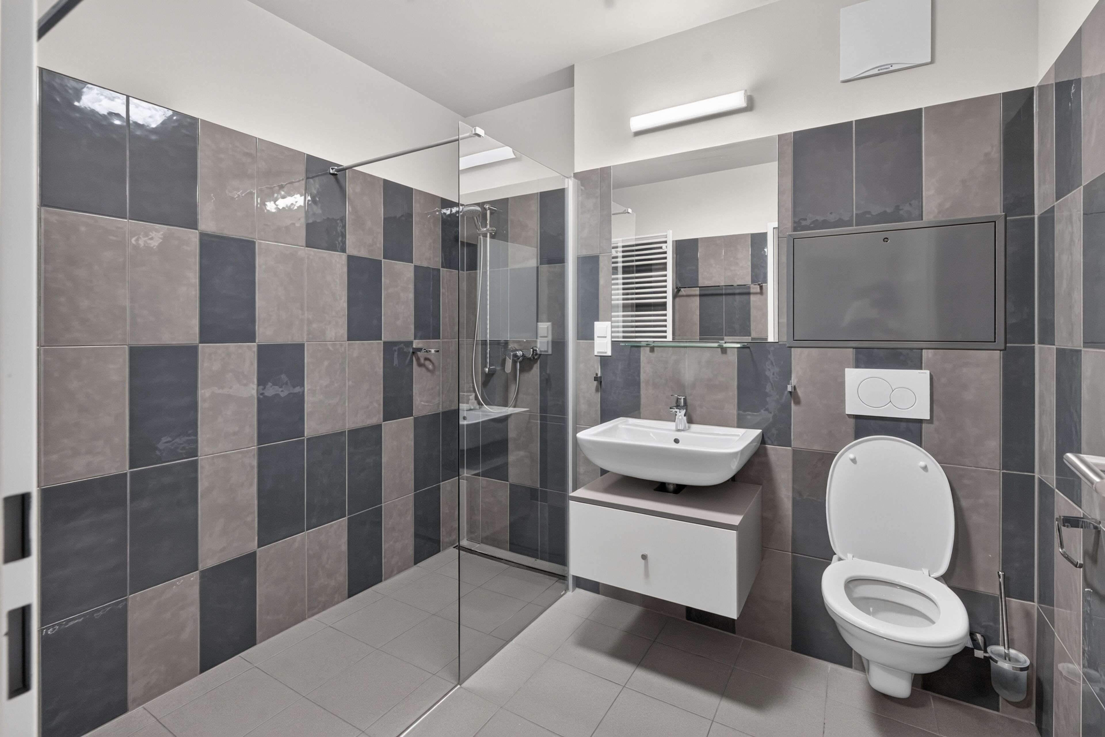 Een moderne badkamer met een douchecabine van glas, een witte wastafel en een toilet.