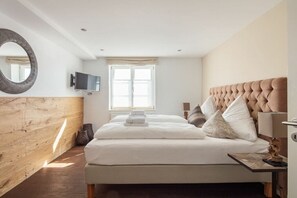 Een hotelkamer met een groot bed, een televisie, een raam met gordijnen en een houten accentmuur.