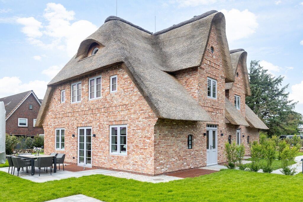Ein Haus mit außergewöhnlichem architektonischen Design, gekennzeichnet durch ein steiles Dach und Ziegelwände.