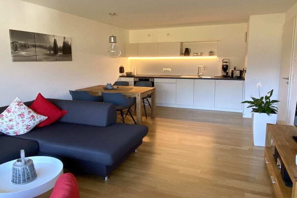 Un salon moderne avec un canapé, une table à manger et une cuisine en arrière-plan.