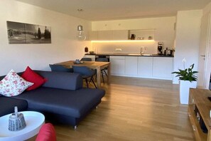 Een moderne woonkamer met een bank, een eettafel en een keuken op de achtergrond.