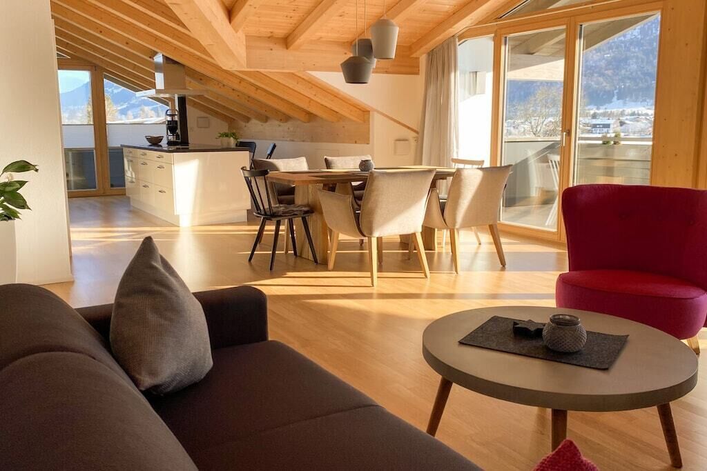 A modern interior with a dining area, a red chair, and a sofa.