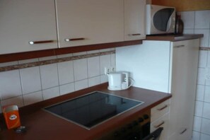 Eine Küche mit weißen Schränken, einer Mikrowelle, einer Kaffeemaschine und einem Herd.