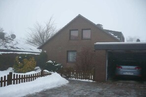 A residential house with a garage, a car parked inside, and snow on the ground. - Stender "An der olen Au" (Winsen)