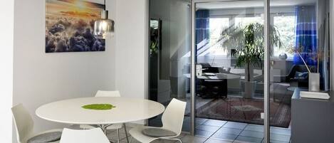 Una sala de reuniones moderna con una mesa redonda, sillas blancas y un panel de vidrio.
