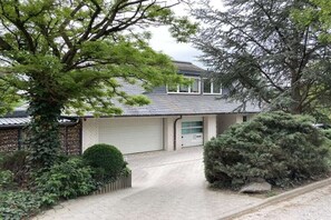 Ein Wohnhaus mit Garage, Auffahrt und umlaufender Bepflanzung.