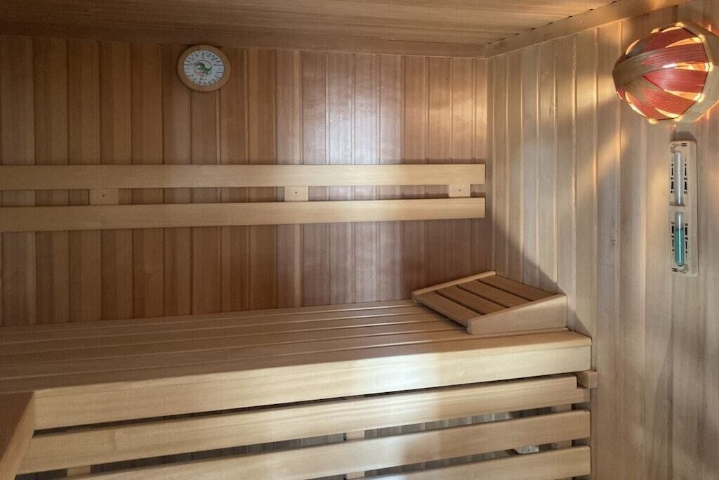 Een houten sauna met banken en een wandheater.