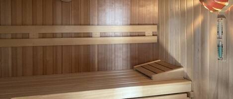 A wooden sauna with benches and a wall-mounted heater.