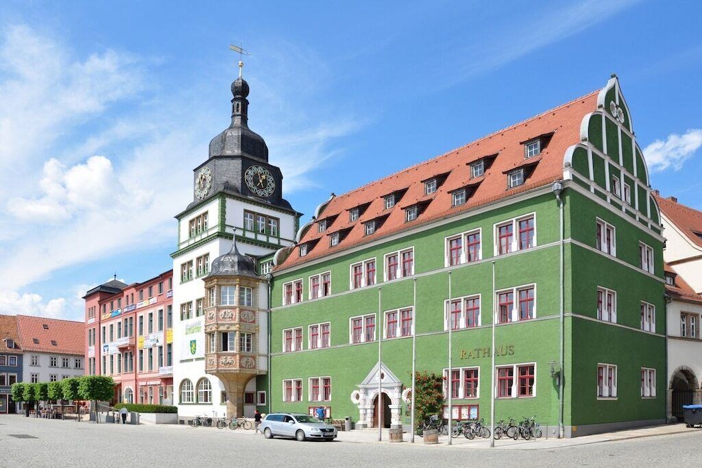 A historic building with a clock tower and a green facade, likely a public or commercial building.