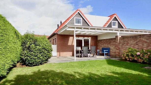Une maison dotée d’un patio couvert, d’une façade en briques et d’une pelouse bien entretenue.