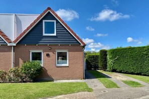 Ein zweistöckiges Haus mit Ziegelverblendung, einem roten Ziegeldach und einem gepflegten Rasen.