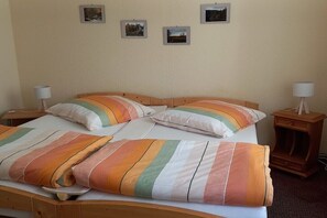 Una cama individual con ropa de cama a rayas, dos mesitas de noche y tres cuadros en la pared.