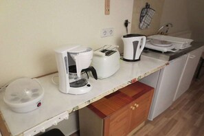 A kitchenette with a coffee maker, toaster, kettle, and a microwave. There is a wooden cabinet below the counter. - Holiday apartment in Teltow with Wi-Fi (Teltow)