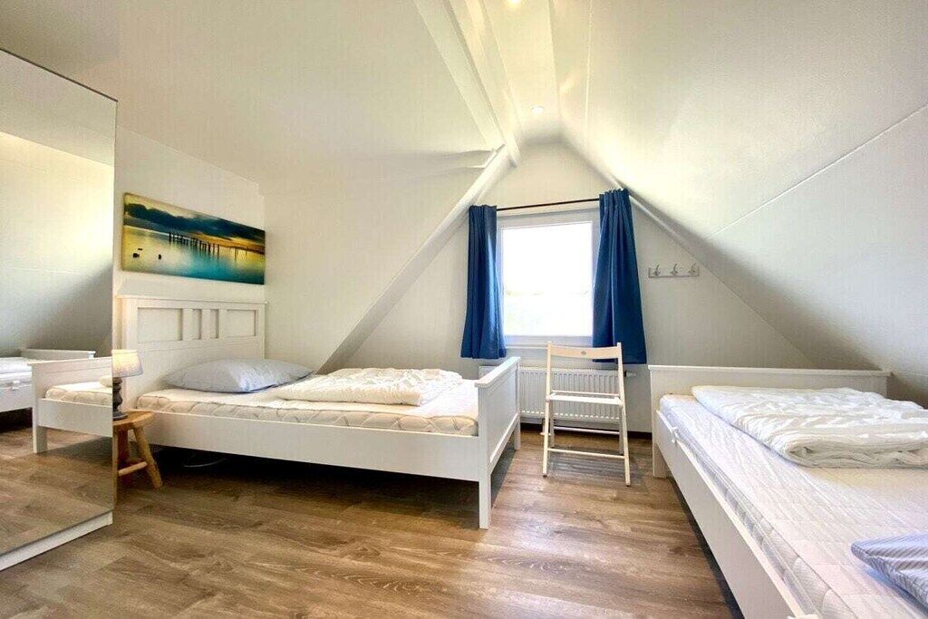 Un dormitorio con dos camas, una ventana con cortinas, un radiador y un cuadro en la pared.