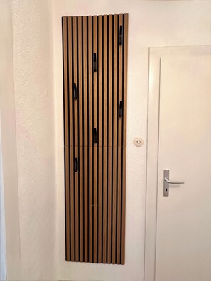 Una puerta blanca con picaporte plateado y un panel de madera vertical con tiradores negros.