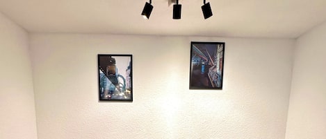 Ein Essbereich mit einem Holztisch, vier schwarzen Stühlen und zwei an der Wand hängenden Bildern.