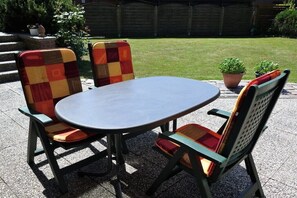 A patio with a round table and four chairs with checkered cushions. - Holiday apartment with 1 bedroom (Kellenhusen)